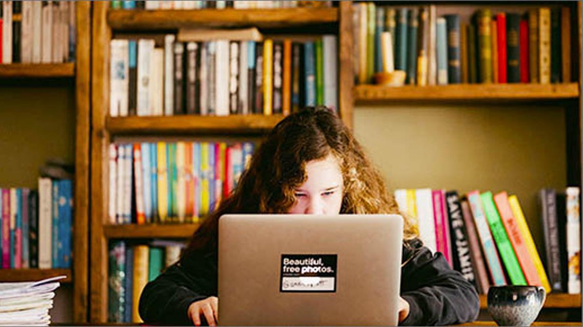  bambina in biblioteca mentre studia sul tablet